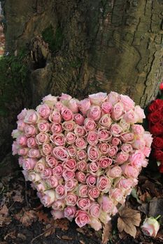 Heart shaped sympathy or funeral flowers near a tree