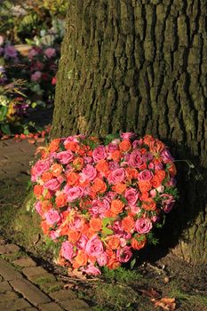 Heart shaped sympathy or funeral flowers near a tree