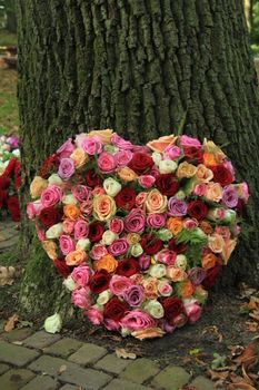 Heart shaped sympathy or funeral flowers near a tree