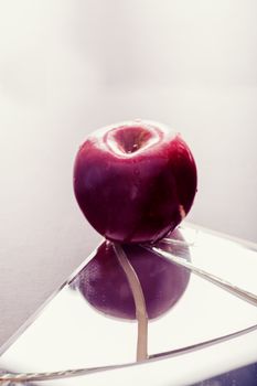 Red apple on cracked broken mirror reflecting