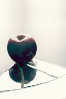 Defocused red apple on cracked broken mirror reflecting