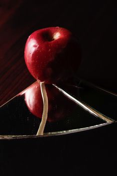 Red apple on cracked broken mirror reflecting