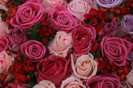 Bridal flower arrangement in various shades of pink and purple, mixed with red berries