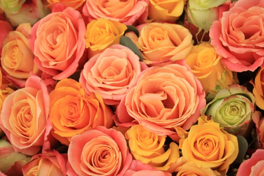 Yellow, orange and pink roses in a floral arrangement at a wedding