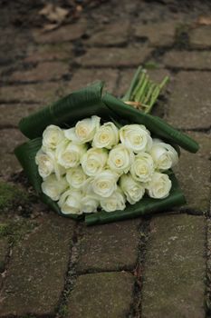 White sympathy roses in a small bouquet on the pavement