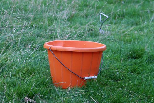 A plastic orange bucket on grass