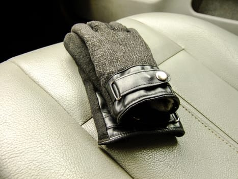 Black Mens Gloves on the Background of Front Leather Seat of A luxury Car