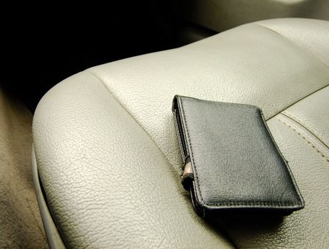 Black Wallet on the Background of Front Leather Seat of A luxury Car