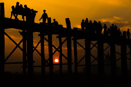 Silhouetted people crossing U bein bridge with sunset,The longest wooden bridge in Mandalay,Myanmar.