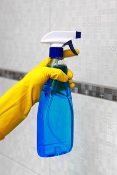 Hand in yellow glove holding spray for cleaning