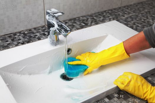 hands of woman in gloves who washes white sink