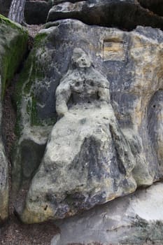 Harpist - Rock Sculptures - sculpture of the girl with a harp sitting next to the monumental relief heads. Statues and reliefs on the rocks carved by sculptor Vaclav Levy in the years 1840 - 1846