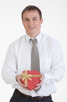 Young man with a heart shaped box in his hand on a white background