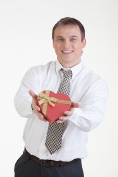 Young man with a heart shaped box in his hand on a white background