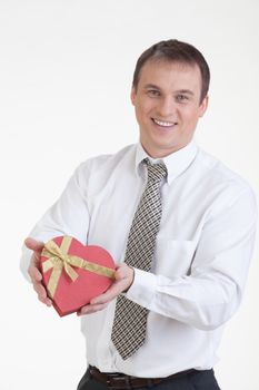 Young man with a heart shaped box in his hand on a white background