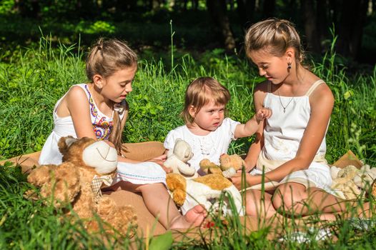 three sisters play toys in Park on the grass