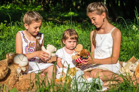 three sisters play toys in Park on the grass