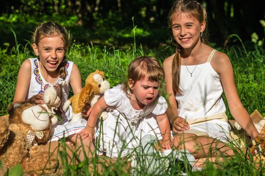 three sisters play toys in Park on the grass