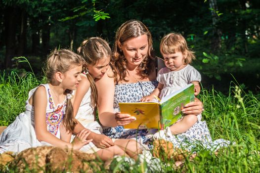 mother reading a book to his daughters in the Park