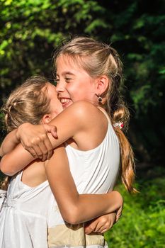 two beautiful daughters hugging and dancing in the park