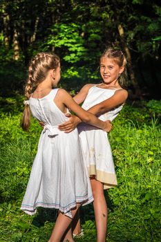 two beautiful daughters hugging and dancing in the park