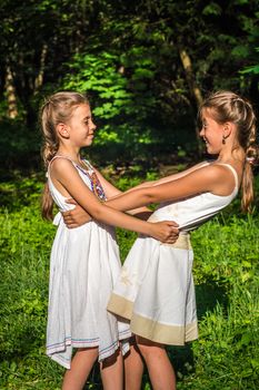 two beautiful daughters hugging and dancing in the park