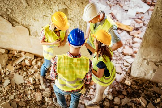 Four construction architects review plan in building damaged in the disaster.