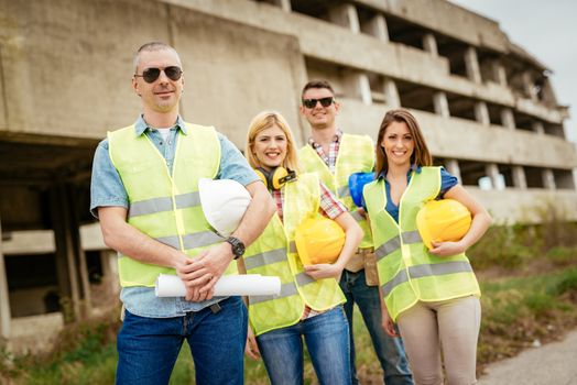 Four construction architects in front building damaged in the disaster. Looking at camera. Selectiv focus.