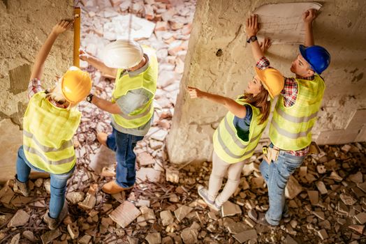 Four construction architects review plan in building damaged in the disaster.