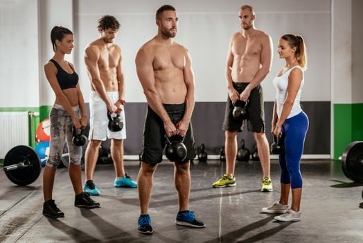 Group of young muscular people doing crossfit exercise at the gym.