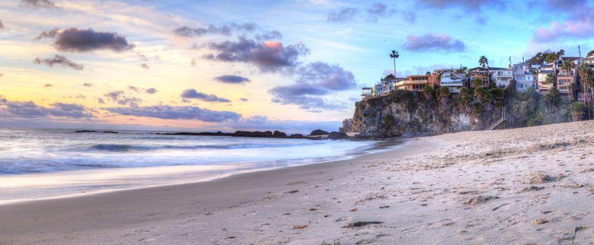 Sunset over the coastline of One Thousand Steps Beach with tidal pools and cliffs in Laguna Beach, California, USA