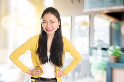 Happy young Asian businesswoman standing in her chain cafe. Female entrepreneur or shop owner.