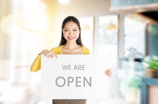 Young Asian woman hand holding "we are open" sign board in restaurant or cafe. 