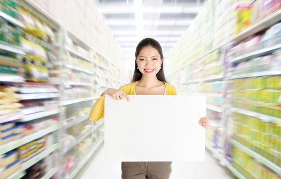 Young Asian woman hand holding a blank white paper card sign board in market or department store. 