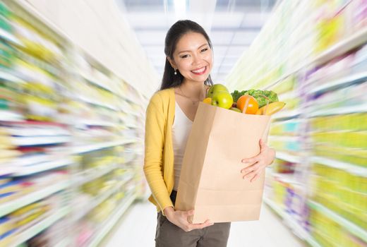 Young Asian woman hand holding shopping paper bag filled with groceries in market or department store. 