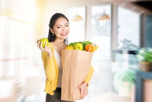 Young Asian female hand holding shopping paper bag filled with fruits and vegetables in market store or cafe .