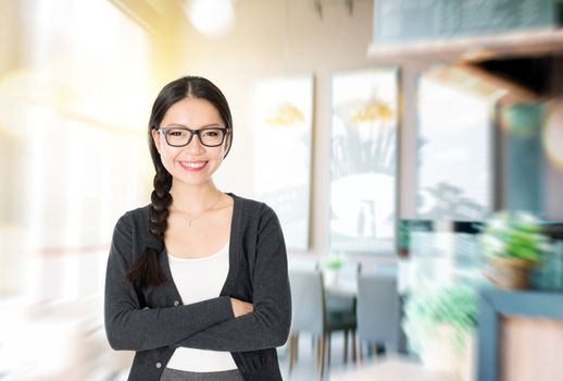 Asian woman arms crossed standing in her cafe. Young female entrepreneur or shop owner.