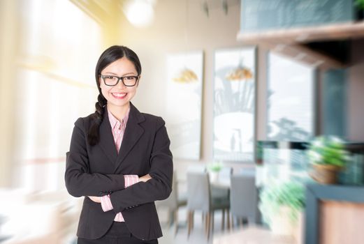 Young Asian businesswoman arms crossed standing in her chain cafe. Female entrepreneur or shop owner.