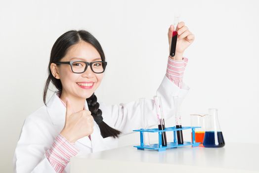 Young Asian female student in microbiological class giving thumb up. Research in science laboratory.