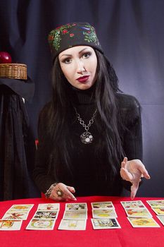 Gypsy woman wonders on the Tarot cards on a black background