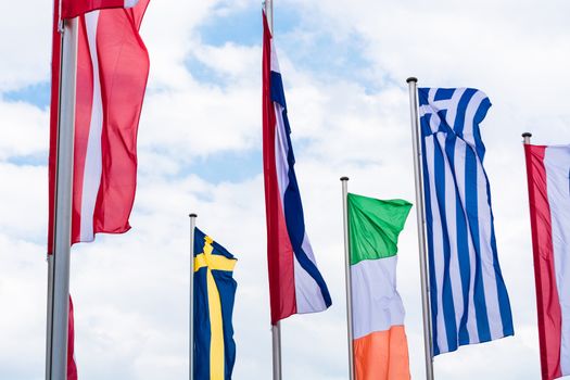 Several Europe countries flags arranged in front of a blue sky.