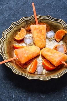 Tasty ice cream with tangerines in copper dish