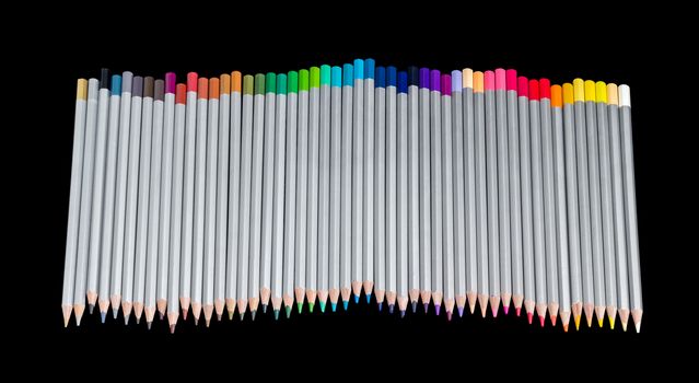 Set of colored pencils in gray wooden case on a dark background
