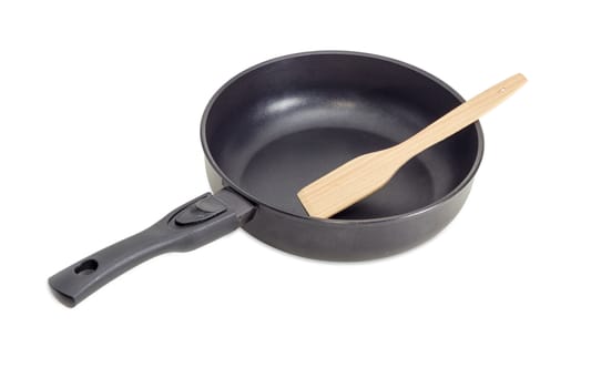 Cast frying pan, made of aluminium alloy with removable handle and wooden spatula on a light background
