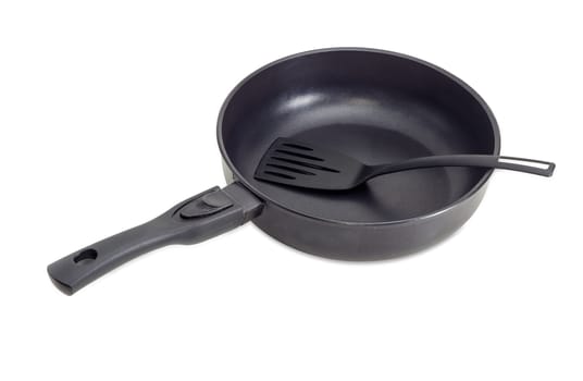 Cast frying pan, made of aluminium alloy with removable handle and plastic spatula on a light background
