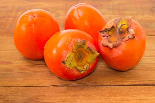 Several ripe fresh persimmons on an old wooden surface
