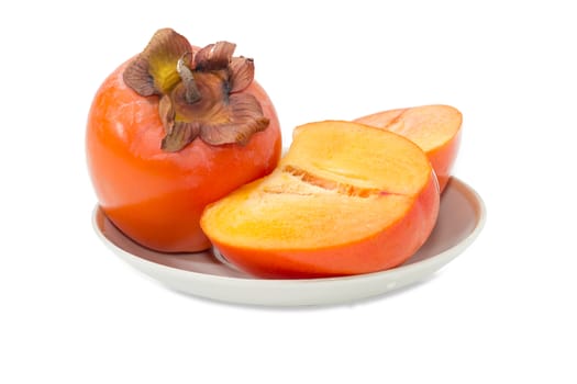 One whole ripe fresh persimmons and one cut in half of a persimmon on saucer on a light background
