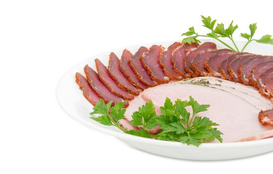 Fragment of white dish with sliced dried pork tenderloin, ham and twigs of parsley closeup on a light background 
