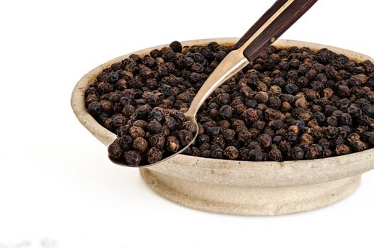 Whole Black Pepper in Old stone bowl and on Spoon