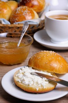 Cut bun with cottage cheese on a plate   and a  knife